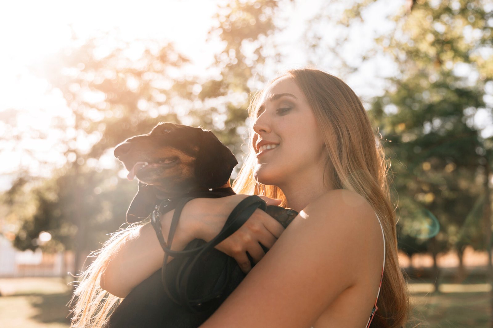 primer plano de una mujer joven disfrutando con su perro en el parque scaled.jpg